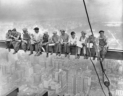 Eleven ironworkers sit on an I-beam high above New York City, with Central Park visible in the background