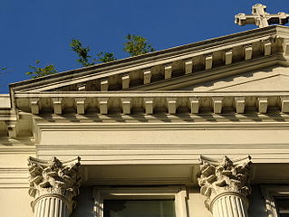 A close-up of the left corner of the pediment of the façade