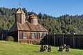 Photograph of a reconstructed blockhouse and palisade wall at Fort Ross, a Northern California forestscape in the background.