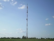 Tall communications tower on flat ground, with guy wires