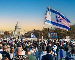 Someone waves the Israeli flag with the U.S. capitol building in the distance.