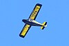 A high-winged small aircraft flies overhead against a clear blue sky, its registration number able to be seen through its blue-and-yellow colors