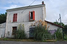 Un bâtiment à l'entrée murée et une voie ferrée en fond.