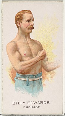 Bare chested man from waist up with raised fists in boxing stance.