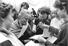 A group of women seeking autographs from an older woman wearing a shawl