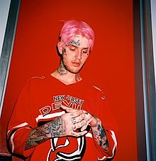 American rapper Lil Peep in front of a red background.