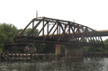 The Philadelphia, Wilmington and Baltimore Railroad Bridge, built 1901-1902 by the American Bridge Company across the Schuylkill River in the Grays Ferry neighborhood in Philadelphia, Pennsylvania, abandoned in open postion ca. 1976. Swing span, 226'-7" long, stone center pier with wood fenders and pilings, and western girder approach. Modern Grays Ferry Avenue bridge in background.