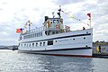 Photograph of the Virginia V at dock on a sunny day, a high-bowed, white vessel with banners and signal flags flying in the wind.