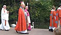 前方(画像右側)の2名がキャソックとスープリスの上にダルマチックを着用。中央の主教の奥にはカトリックの司教の姿がある。写真左・後方の人物は、アルブキャソックに赤いストールを着用した司祭。