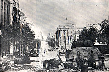 Photograph of a destroyed tank in a street