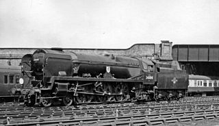 A posed side-and-front view of the rebuilt form of the locomotive, standing in the sidings of a locomotive depot. The locomotive is of conventional appearance, with a visible boiler and no flat covering plates. Smoke deflectors are fitted at the front of the locomotive.