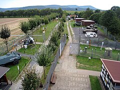 Vue élevée d'une série de cabanes et de véhicules exposés en plein air de chaque côté d'une route de patrouille bétonnée.