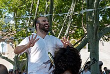 Un homme barbu debout en train de rire.