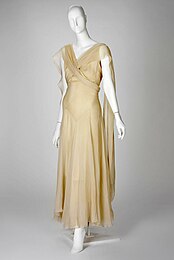 Beige ankle-length sleeveless dress with pieces draped over the shoulder