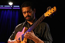 un homme barbu avec une guitare sur scène