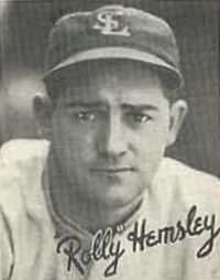 A man in a light baseball uniform and dark cap with "SL" on the center.