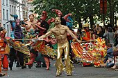 Carnival-style dancer and processional puppets parading through the streets of Brussels