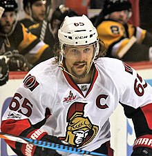 man with mustache and beard wearing a white ice hockey uniform