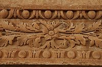 Photographie de la partie centrale du linteau de la porte du minaret. D'origine antique (morceau de soffite), il est orné d'un décor sculpté de pampres et de perles.