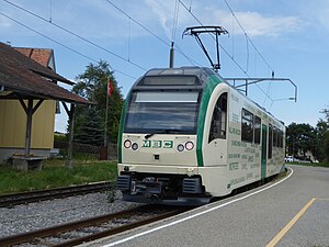 White and green train next to a station platform