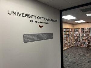 An image of the UT Press office, with its logo and title on the wall and a bookshelf in the background.