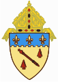The arms of the Diocese of Baton Rouge: The shield features a red baton, referencing the city name, Baton Rouge, Louisiana, and its literal French meaning.