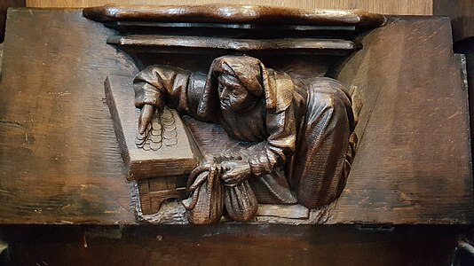 Detail of a misericord on a choir stall, showing a money-changer