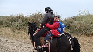 Mère emmenant son enfant à l'école à cheval, en Chine.