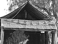 Fig. 9: The northern gable-end was fashioned by nailing sheets of galvanized iron onto a sub-frame. Insecurely fastened to the main structure, it has fallen out.