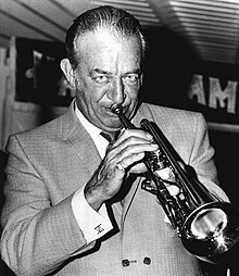 Black and white photo portrait of a man in a suit playing the trumpet