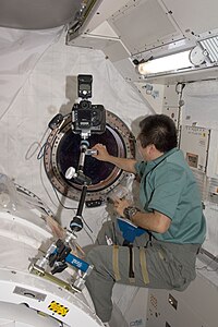 Mise en place d'une caméra devant un des deux hublots du module Kibō.