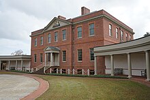 A photo of a colonial brick mansion viewed from a side angle