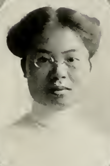 A young Chinese woman wearing eyeglasses and a high-collared white blouse; her hair is parted center and dressed in an updo