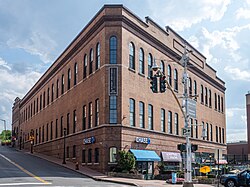 A large three-story brick building with storefronts on the bottom, rounded-arch windows on the second and third levels and a parapet on top.