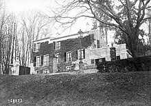 Vue d'ensemble d'une maison à un étage comprenant cinq fenêtres à chaque niveau et un treillage sur la façade.