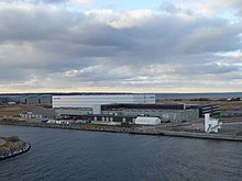 Hangar logistique blanc situé dans une zone portuaire.