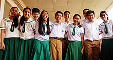 Ten students stand together. All are wearing their school uniforms.