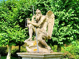 stone statue of winged Father Time with staff and hourglass