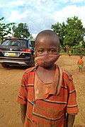 Enfant portant un masque végétal dans un village.