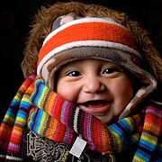 Baby in heavy winter clothing including a woollen scarf