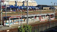 Abri de quai en béton tagué desservi par les trains en provenance de Savenay avec en fond un bateau des Chantiers de l'Atlantique en construction.