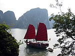 Traditional red sails on Hạ Long style's boat contrast with blue water surface