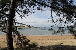 A photograph of a narrow strip of water separating two land masses linked by the Noirmoutier Bridge