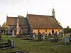 A church seen from the north, with an extensive roof. On the right is the nave with a bellcote at the west end; on the left is the chancel with the vestry.