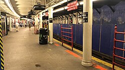 A platform and track, with a blue construction wall blocking off the space behind the track