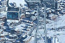 Vue d'une télécabine au premier plan et du village enneigé au second