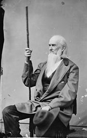 A black and white photograph of Duff Green, with a very long beard and wooden staff, seated.