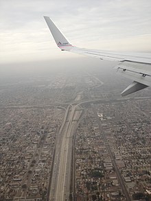 On voit l'aile d'un avion en haut de l'image, l'échangeur en bas avec de part et d'autre des habitations. (2013)