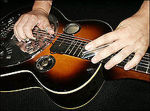 A resonator (acoustic) guitar played in lap steel fashion. The bar is held on a slant.