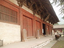 The front of a Chinese temple building. It is painted white with red trim.